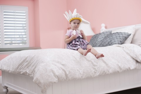 USA, Utah, small girl (2-3) with plume sitting on bed. Photo : Tim Pannell