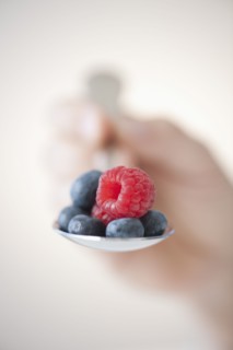 Blueberries and raspberry on spoon.