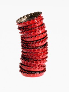 Studio shot of heap of red bottle caps. Photo : David Arky