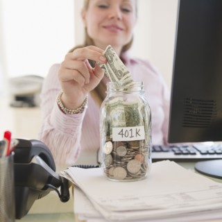 USA, New Jersey, Jersey City, Businesswoman putting money into piggybank. Photo : Jamie Grill