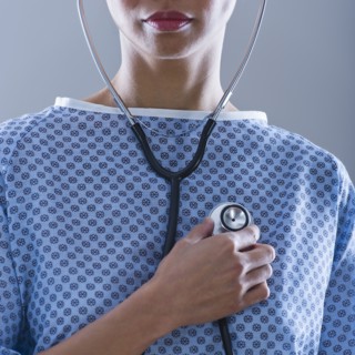 Female patient holding stethoscope to chest.