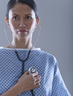 Female patient holding stethoscope to chest.