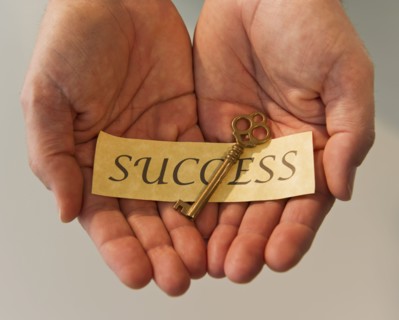 Hands holding key and label reading Success. Photo : Daniel Grill