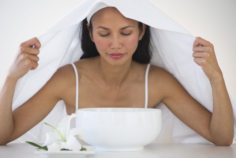 Woman under towel having steam beauty treatment.