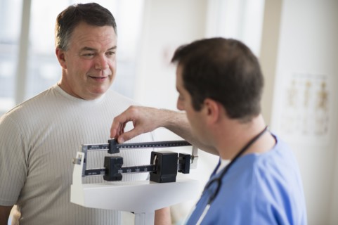 USA, New Jersey, Jersey City, Doctor assisting male patient on weighing scales in hospital.