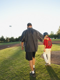USA, California, Ladera Ranch, man and boy (10-11) walking on baseball field.