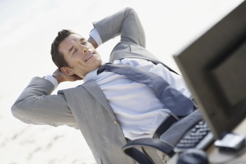 South Africa, Relaxed businessman sitting with laptop in office. Photo : momentimages