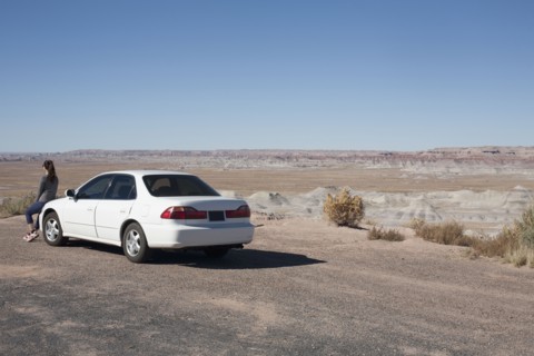 USA, Arizona, Painted Desert. Little Painted Desert, Woman leaning on car and looking at view.