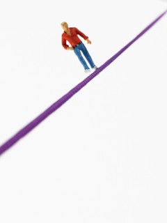 Studio shot of male figurine balancing on tightrope. Photo : David Arky