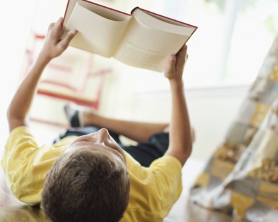 USA, Utah, Boy (10-11) reading book on floor. Photo : Tim Pannell