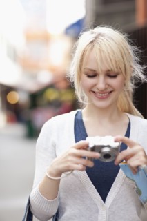 USA, Seattle, Smiling young woman holding digital camera. Photo : Take A Pix Media