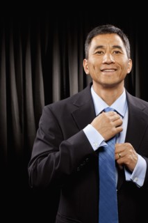 USA, Utah, Provo, Portrait of businessman standing in front of black curtain and adjusting tie.