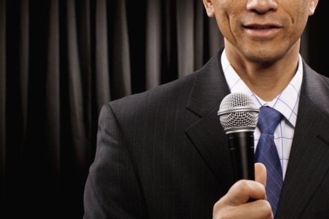 USA, Utah, Provo, Close-up of businessman with microphone standing in front of black curtain, mid