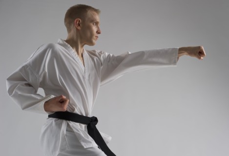 Young man performing karate stance on white background.