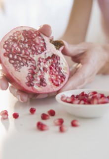 USA, New Jersey, Jersey City, Womans hand with pomegranate cross-section. Photo : Jamie Grill