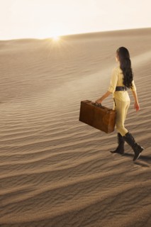 USA, California, Death Valley, Woman with suitcase walking in desert.