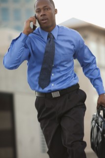 USA, Utah, Salt Lake City, Young businessman running and talking on mobile phone. Photo : Mike Kemp