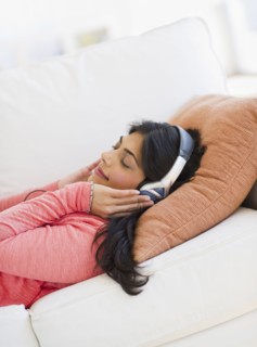 USA, New Jersey, Jersey City, Young attractive woman laying on back listening to music. Photo :