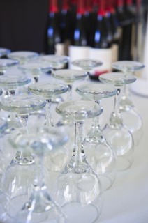 Wine glasses on table with bottles in background.