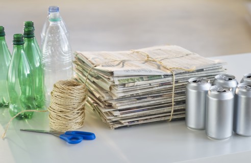 Recycling bottles, cans and newspapers with scissors and string.