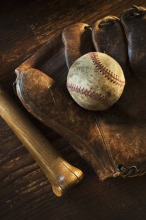 Antique baseball on baseball glove with bat.