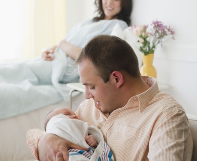USA, New Jersey, Jersey City, father embracing baby daughter (2-5 months) with mother in background