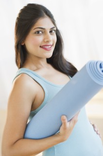 USA, New Jersey, Jersey City, Pregnant young attractive woman with exercising mat. Photo : Daniel