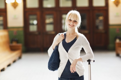 USA, Seattle, Young woman at train station standing with luggage and looking at camera. Photo :