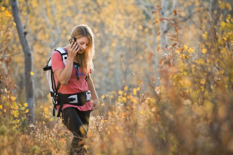 USA, Utah, young woman hiking in forest and talking on mobile phone. Photo : Mike Kemp