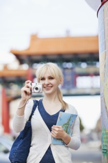 USA, Seattle, Young woman taking photos and holding map. Photo : Take A Pix Media