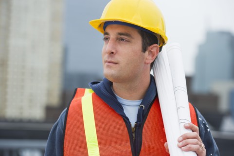 USA, New Jersey, Jersey City, Construction worker holding blueprints on construction site.