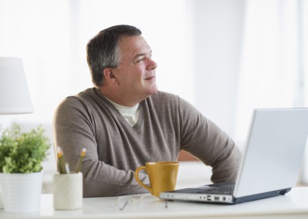 USA, New Jersey, Jersey City, Pensive man using laptop in living room.