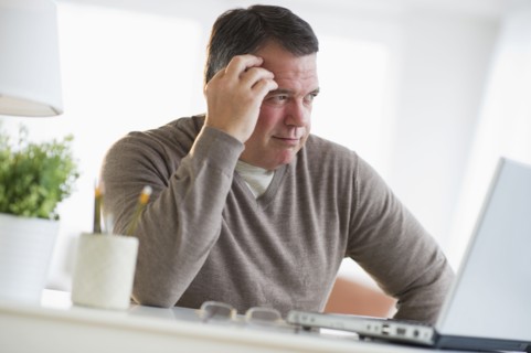USA, New Jersey, Jersey City, Pensive man using laptop in living room.