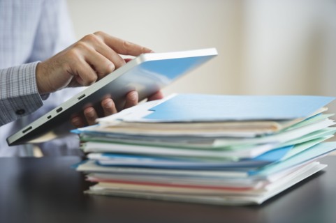 USA, New Jersey, Jersey City, Businessman using digital tablet by paperwork.