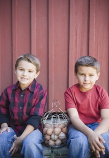 USA, New York, Flanders, Brothers (4-5, 8-9) posing with basket of eggs. Photo : Jamie Grill