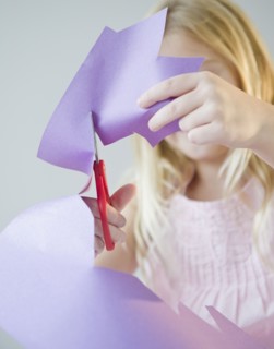 USA, New Jersey, Jersey City, Girl (8-9) cutting star shape in paper. Photo : Jamie Grill