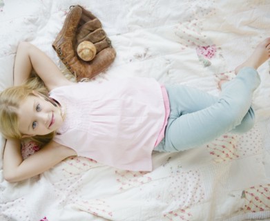 USA, New Jersey, Jersey City, Girl (8-9) laying beside baseball glove and ball. Photo : Jamie Grill