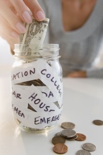 USA, New Jersey, Jersey City, Close-up view of woman's hand putting one dollar bill into piggybank.