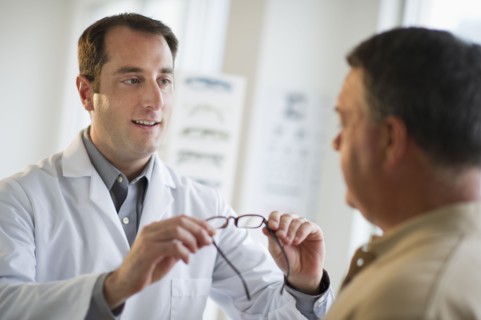 USA, New Jersey, Jersey City, Optician showing man glasses in shop.