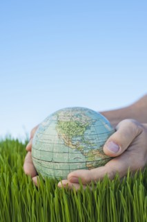 Male hands holding globe over grass.