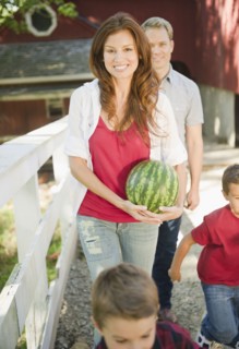 USA, New York, Flanders, Mother holding water melon while boys (4-5, 8-9) are messing about, father