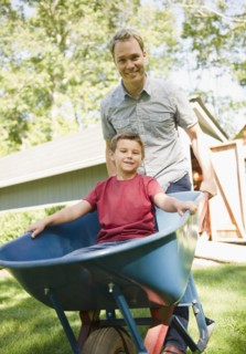 USA, New York, Flanders, father pushing wheel barrow with son (8-9) inside. Photo : Jamie Grill