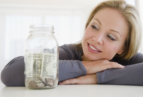USA, New Jersey, Jersey City, Young attractive woman watching improvised jar - piggybank. Photo :