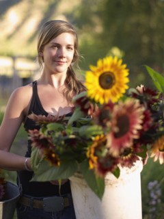 USA, Colorado, Young woman carrying bucket with sunflowers. Photo : John Kelly