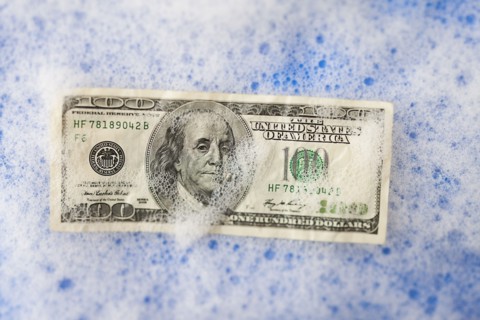 One hundred dollar bill soaking in soap sud. Photo : Mike Kemp