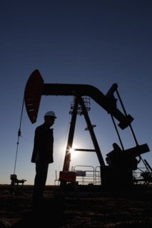 Silhouette of oil worker by pump jack on rig. Photo : Dan Bannister