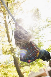 USA, Utah, rear view of girl (6-7) hanging on rope. Photo : Tim Pannell