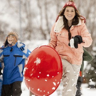 USA, Utah, Provo, Teenage (16-17) girl running with sledge, boys and girls (10-11, 12-13) in