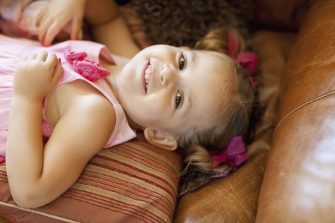 Happy girl lying on sofa, high angle view. Photo : FBP