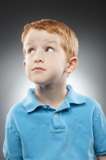 Portrait of smiling redhead boy (4-5) wearing blue polo shirt and looking up, studio shot. Photo :